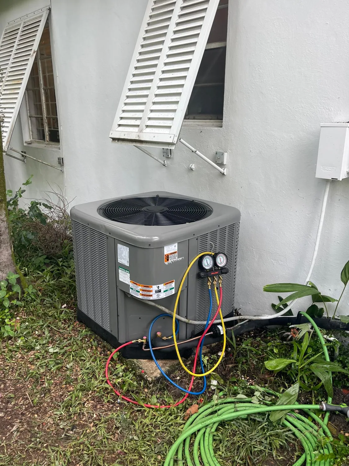 Freshly serviced AC condenser with refrigerant gauges in Miami-Dade